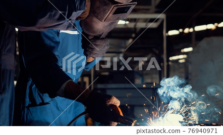 Skillful metal worker working with arc welding machine in factory Skillful metal worker working with arc welding machine in factory 76940971