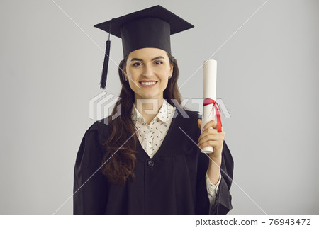 Portrait of a smart and successful female graduate with a diploma in her hands on a gray background. Portrait of a smart and successful female graduate with a diploma in her hands on a gray background. 76943472