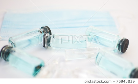 Vial vaccine, top view of glass ampoules with transparent and blue liquid lying on white background, global vaccination concept 76943839