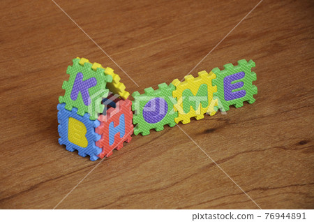 HOME word made from colourful soft rubber mat. Isolated on a wood texture board background.  76944891