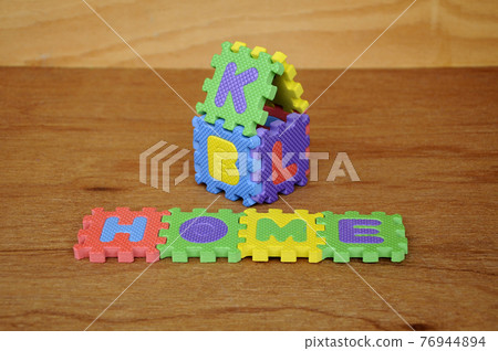 HOME word made from colourful soft rubber mat. Isolated on a wood texture board background.  76944894