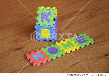 HOME word made from colourful soft rubber mat. Isolated on a wood texture board background.  76944897