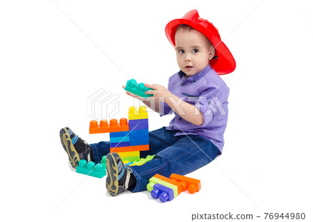 Child plays builder with constructor sitting on the floor 76944980