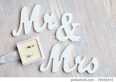 Wedding rings in a box next to the inscriptions Mr and Mrs on a wooden background. 76948545