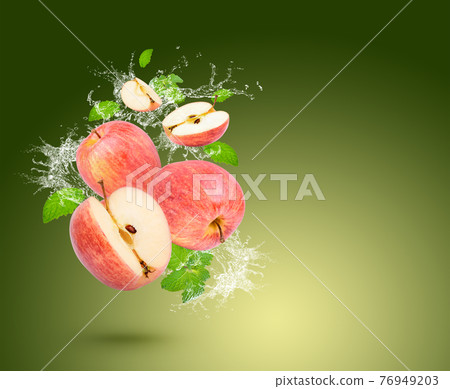 Water splash on fresh apple with mint leaves isolated on green background. Water splash on fresh apple with mint leaves isolated on green background. 76949203