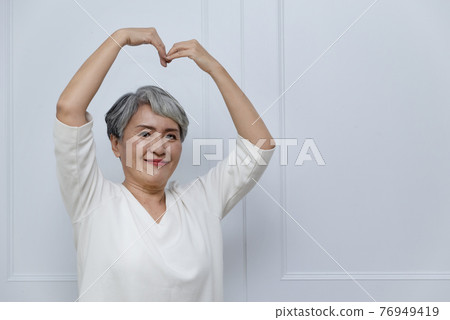 Silver-haired woman showing heart shape 76949419