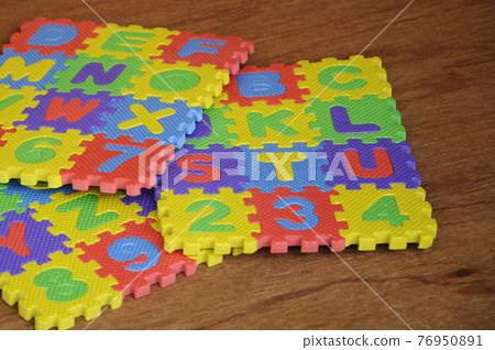 Rubber mat with colorful alphabet design isolated on wood texture board as background.   76950891