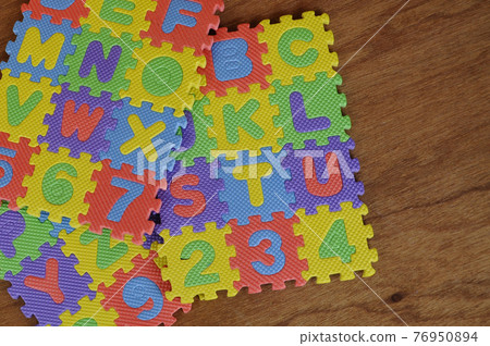 Rubber mat with colorful alphabet design isolated on wood texture board as background.   76950894