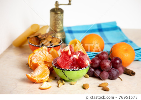 Turkish delight or lokum in a green bowl with grapes, mandarines, nuts, spices - a great arabic dessert. Turkish delight or lokum in a green bowl with grapes, mandarines, nuts, spices - a great arabic dessert. 76951575