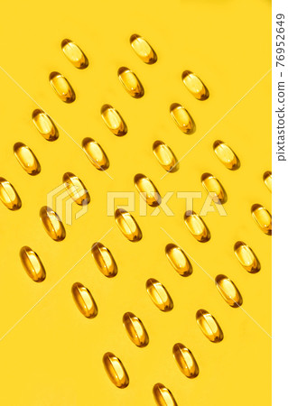 Yellow oval pills capsules vitamin Omega 3 over yellow Yellow oval pills capsules vitamin Omega 3 over yellow 76952649
