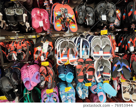 KUALA LUMPUR, MALAYSIA -AUGUST 18, 2020: Colorful pair of slippers and shoes displayed for sale. Each pair has a price tag for the convenience of customers. 76953944