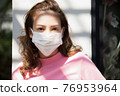 年輕女子站在外面戴著口罩 76953964
