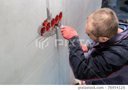 The electrician will plaster holes and channels for sockets and wires. 76954120