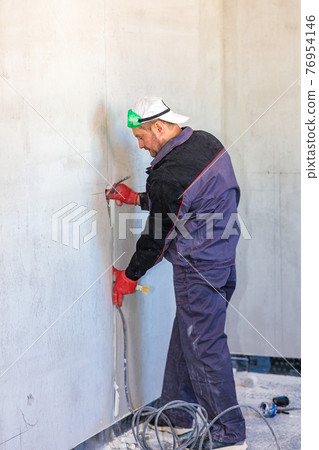 An electrician is laying a cable in an electrical wiring ditch An electrician is laying a cable in an electrical wiring ditch 76954146