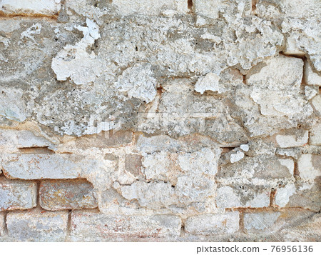 Vintage brick wall with peeled damaged plaster 76956136