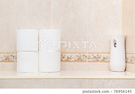 Rolls of white toilet paper and air freshener on the toilet shelf. Rolls of white toilet paper and air freshener on the toilet shelf. 76956145