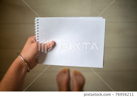 top view of a hand with silver bracelet holds a white empty paper notepad with copyspace,creative top view of a hand with silver bracelet holds a white empty paper notepad with copyspace,creative 76956211