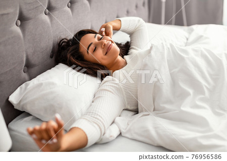 Happy young African American woman stretching after waking up 76956586