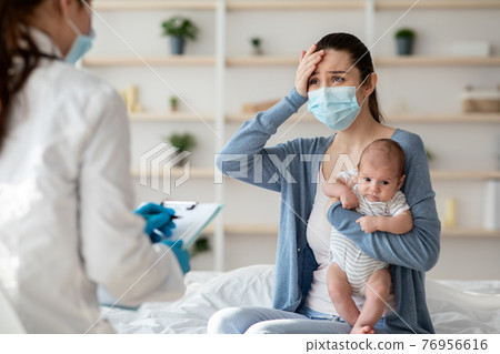 Mother In Protective Mask Holding Newborn Baby, Explaining Illness Symptoms To Doctor Mother In Protective Mask Holding Newborn Baby, Explaining Illness Symptoms To Doctor 76956616