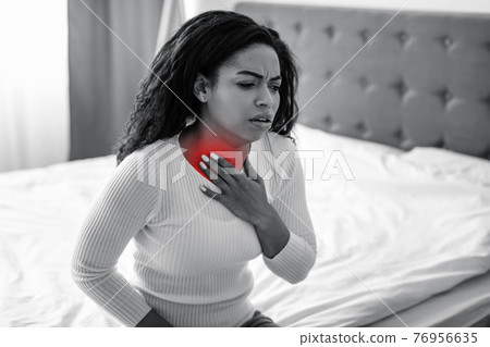 Young black woman coughing, suffering from sore throat Young black woman coughing, suffering from sore throat 76956635