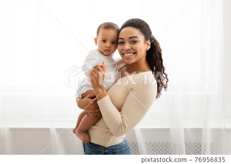 Black Mom Holding Little Infant Smiling To Camera Posing Indoors 76956835