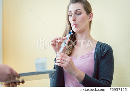 Woman in hospital breathing in tube to test for respiratory disease Woman in hospital breathing in tube to test for respiratory disease 76957135
