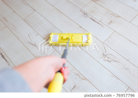 Woman cleaning floor with yellow mop at home. Microfiber mop isolated on white wooden floor background, closeup, indoors 76957796