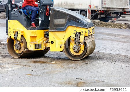 The compact road roller works by compacting the base of the roadway. 76958631