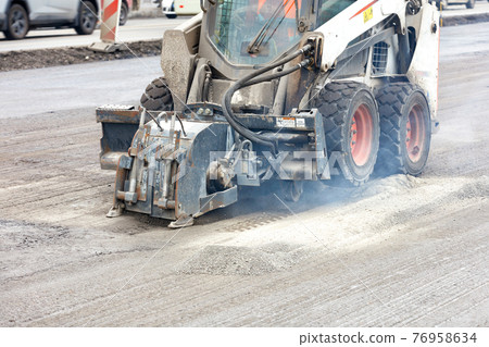 Compact road tractor with hydraulic attachment cuts cracks when repairing road foundations. 76958634