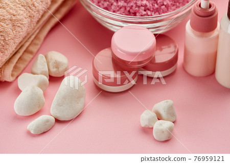 Skin care products and pebbles on pink background 76959121