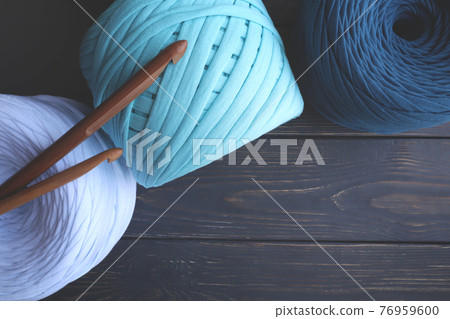 Colorful skeins of yarn and crochet hooks on a gray wooden background with space for text. The concept of hobbies, crafts. 76959600