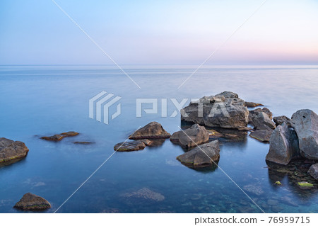 Twilght over the wild rocky beach coastline and the sea. Sea and rocks at night wide angle view. Twilght over the wild rocky beach coastline and the sea. Sea and rocks at night wide angle view. 76959715