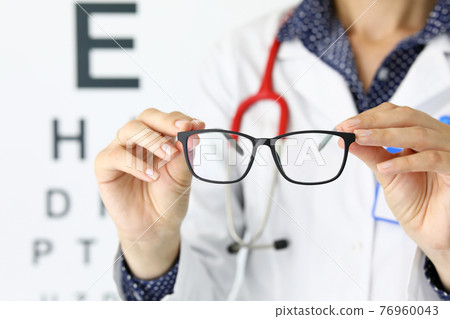 Close-up of person holding black stylish glasses with perfect frame Close-up of person holding black stylish glasses with perfect frame 76960043