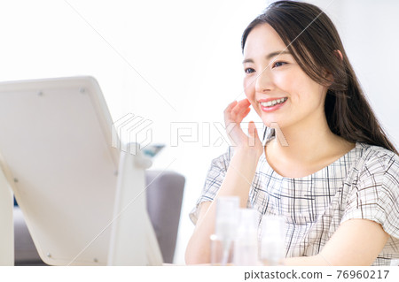 Young woman looking at a mirror 76960217