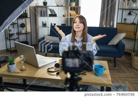 Woman sitting at table with laptop and recording video 76960596
