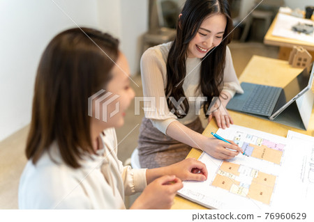 兩個女人一邊看房子的平面圖一邊開會的商業場景 兩個女人一邊看房子的平面圖一邊開會的商業場景 76960629
