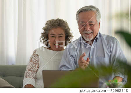 Couple Elderly Asian video conferent online with laptop at home. 76962548