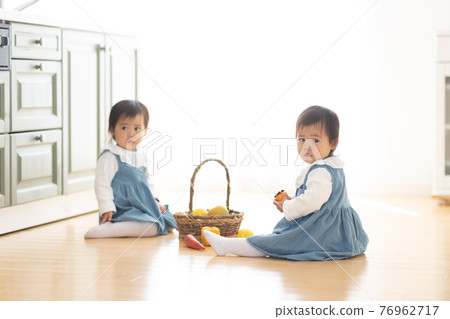 Cute twin toddlers playing in the room 76962717