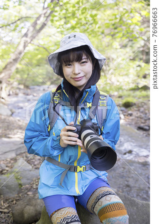 一位年輕女子在山上用單鏡頭反光相機徒步旅行的照片 76966663