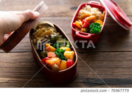 Handmade bento, a woman's hand that closes the lid Handmade bento, a woman's hand that closes the lid 76967779