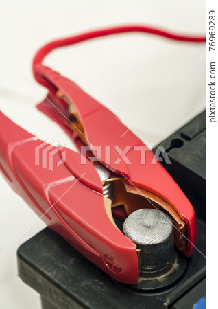 Recharging the car battery. Red copper clip attached to the plus terminal. 76969289