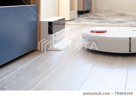 Robotic vacuum cleaner on laminate wood floor with charging base station - technology housework Robotic vacuum cleaner on laminate wood floor with charging base station - technology housework 76969294