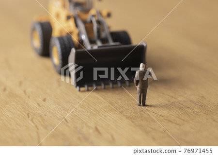 A businessman who stops a wheel loader A businessman who stops a wheel loader 76971455