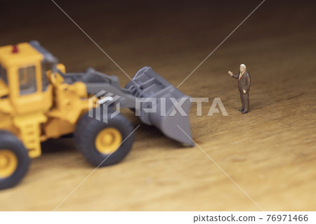 A businessman who stops a wheel loader A businessman who stops a wheel loader 76971466