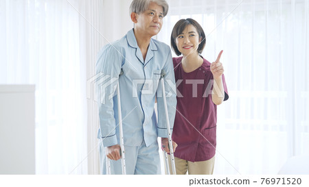 幫助中年男子拄拐杖行走的女傭 76971520
