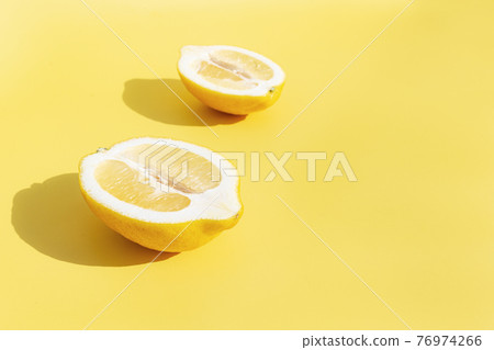 Two halved cuts of lemon with shadow on yellow background 76974266