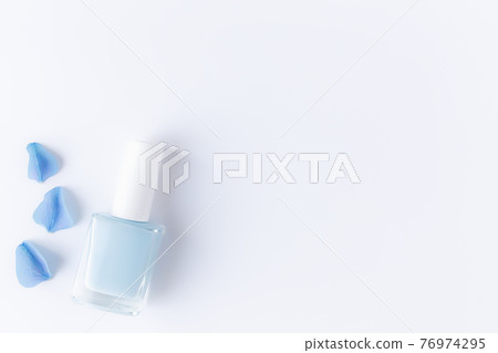 Blue petals with nail polish in transparent glass bottle, white background 76974295