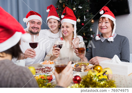 Family at dining table for Christmas dinner Family at dining table for Christmas dinner 76974975