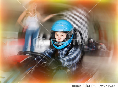 Happy female go-cart racer crossing finish line 76974982
