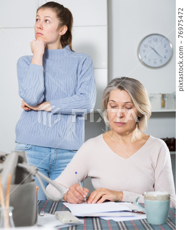 Sad young female and mother with financial documents 76975472